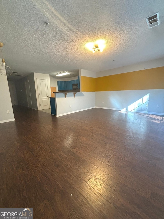 unfurnished living room with dark hardwood / wood-style floors and a textured ceiling