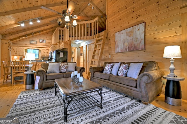 living room featuring beam ceiling, track lighting, wooden walls, and wood ceiling