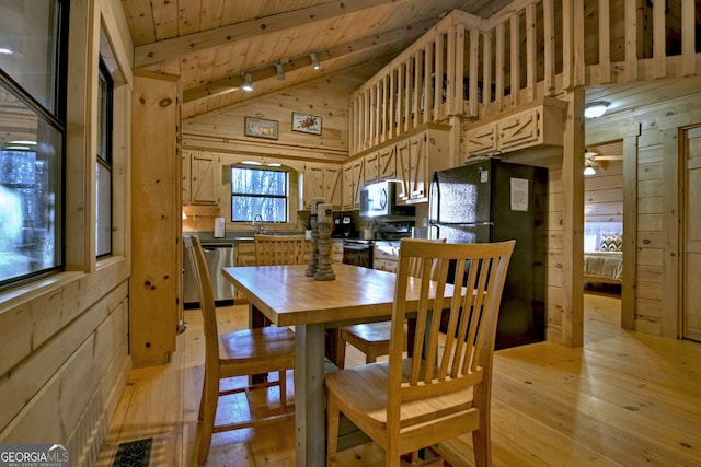 dining area with wood walls, wooden ceiling, rail lighting, vaulted ceiling with beams, and light hardwood / wood-style floors