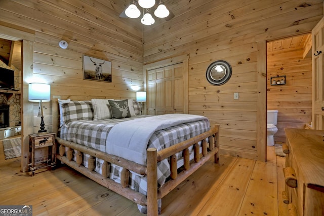 bedroom with light hardwood / wood-style flooring, a closet, and wooden walls