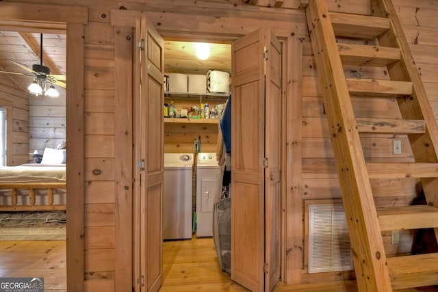 interior space featuring ceiling fan, wooden ceiling, washing machine and dryer, wood walls, and light wood-type flooring