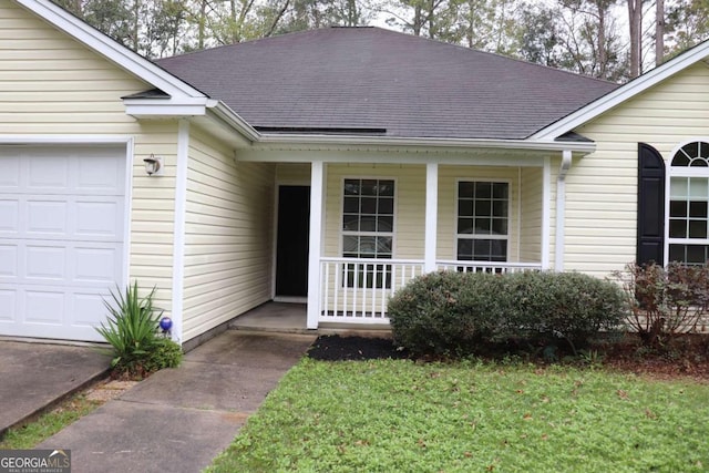 view of exterior entry featuring a yard, covered porch, and a garage