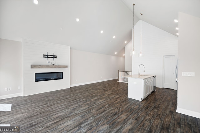 unfurnished living room with dark wood-type flooring, sink, a fireplace, and high vaulted ceiling