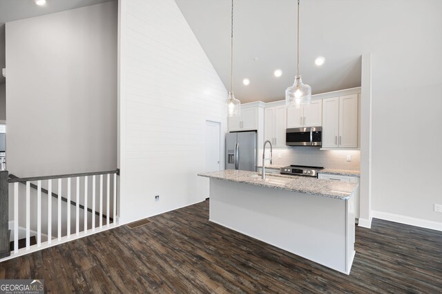 kitchen featuring decorative light fixtures, decorative backsplash, white cabinetry, light stone countertops, and stainless steel appliances