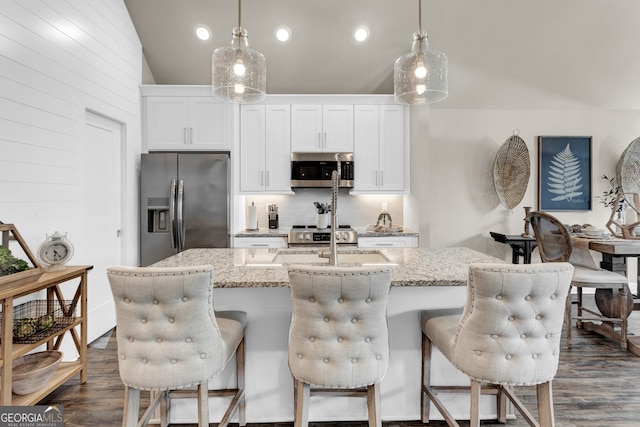 kitchen featuring white cabinetry, appliances with stainless steel finishes, a kitchen island with sink, and tasteful backsplash