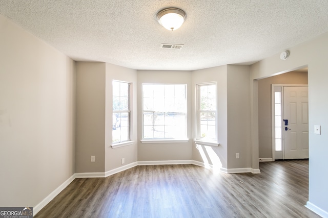 unfurnished room with dark hardwood / wood-style flooring, plenty of natural light, and a textured ceiling