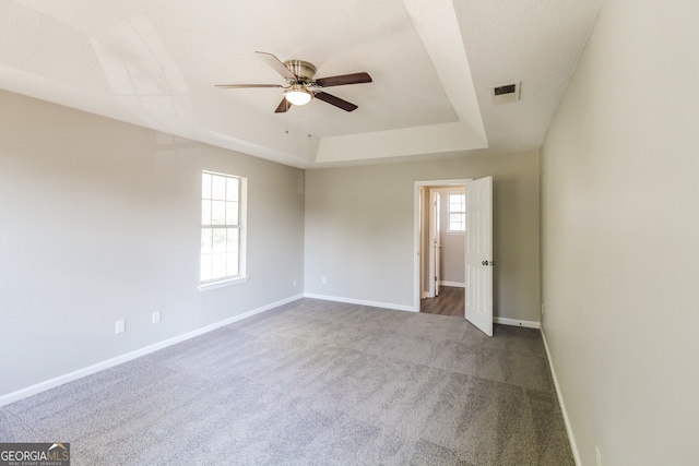 empty room with carpet, a raised ceiling, and ceiling fan