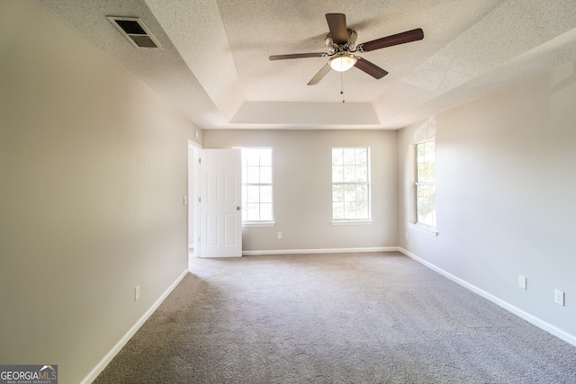 carpeted empty room with a textured ceiling, a tray ceiling, and ceiling fan