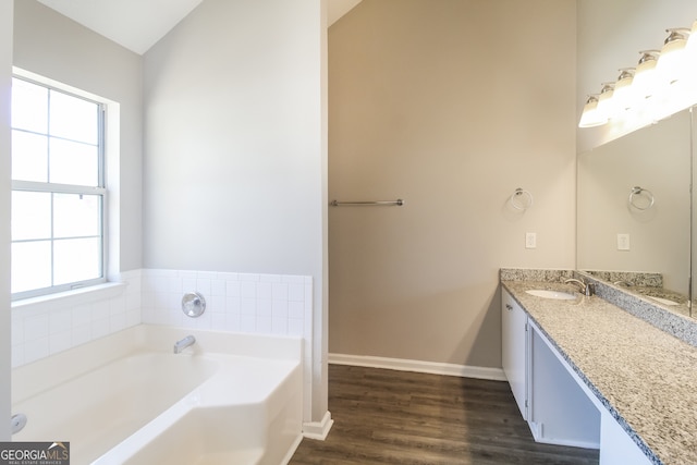 bathroom with a bath, plenty of natural light, hardwood / wood-style floors, and vaulted ceiling