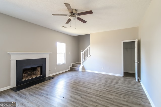 unfurnished living room with hardwood / wood-style flooring, ceiling fan, and a textured ceiling