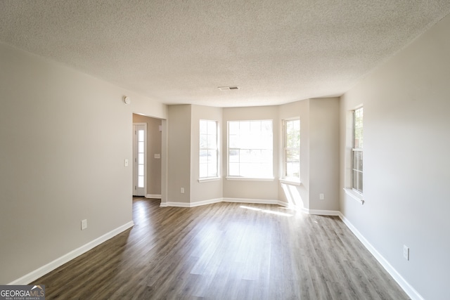 unfurnished room featuring hardwood / wood-style flooring and a textured ceiling