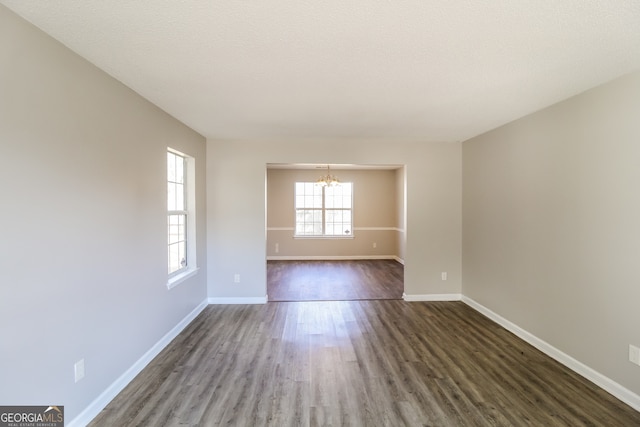 unfurnished room with dark hardwood / wood-style flooring, a textured ceiling, and an inviting chandelier