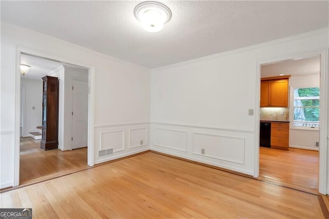 unfurnished room featuring ornamental molding, a textured ceiling, and light hardwood / wood-style flooring