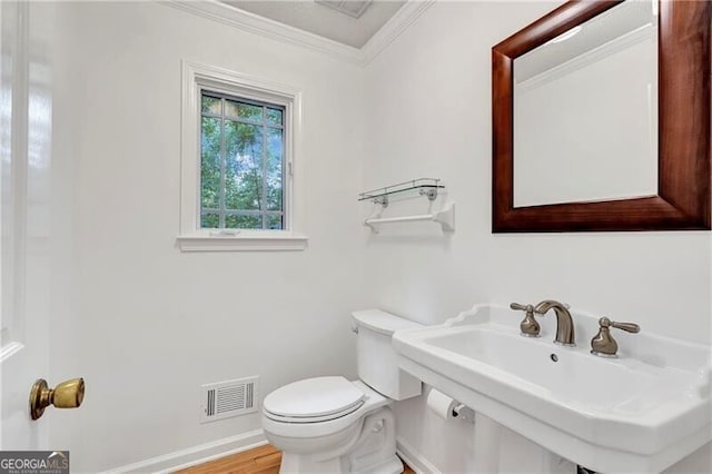 bathroom featuring hardwood / wood-style flooring, toilet, sink, and ornamental molding