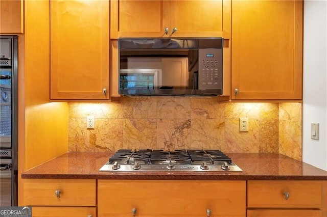 kitchen with stainless steel gas stovetop, backsplash, and dark stone counters