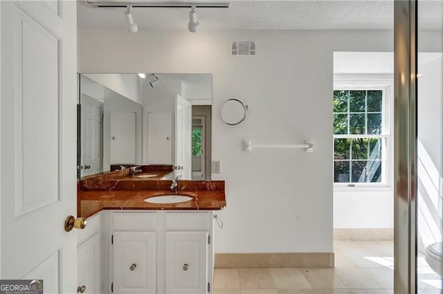 bathroom featuring tile patterned flooring, vanity, track lighting, and a textured ceiling