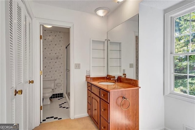 bathroom with toilet, vanity, tile patterned floors, and a shower with shower door