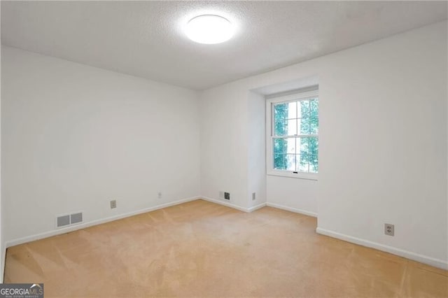 carpeted empty room with a textured ceiling