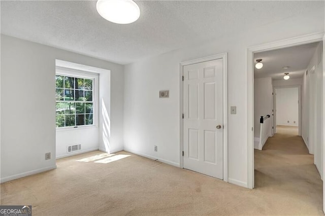 carpeted empty room featuring a textured ceiling