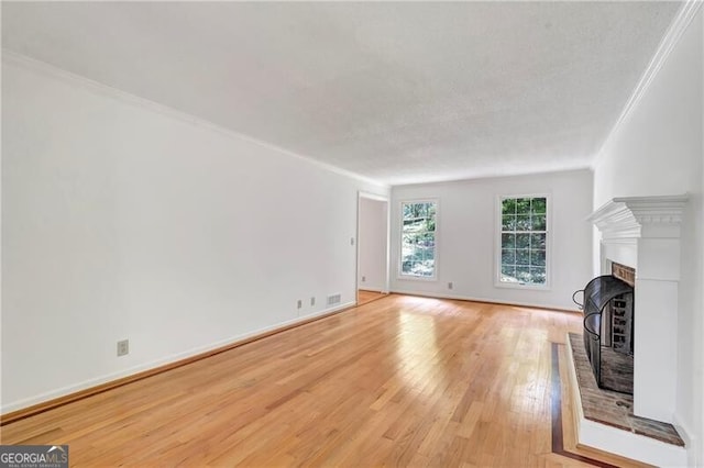 unfurnished living room featuring a fireplace, crown molding, light hardwood / wood-style flooring, and a textured ceiling