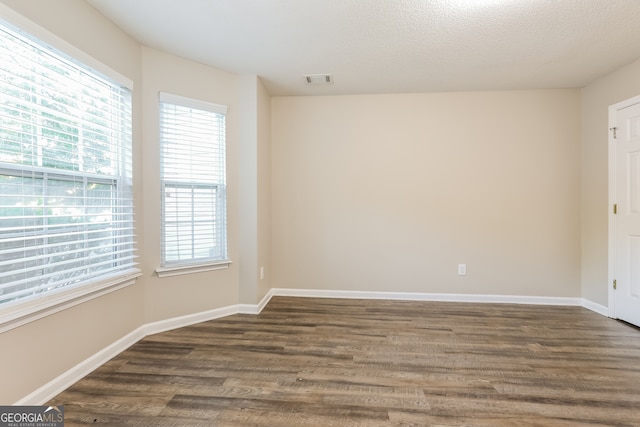 empty room with a textured ceiling and dark hardwood / wood-style floors