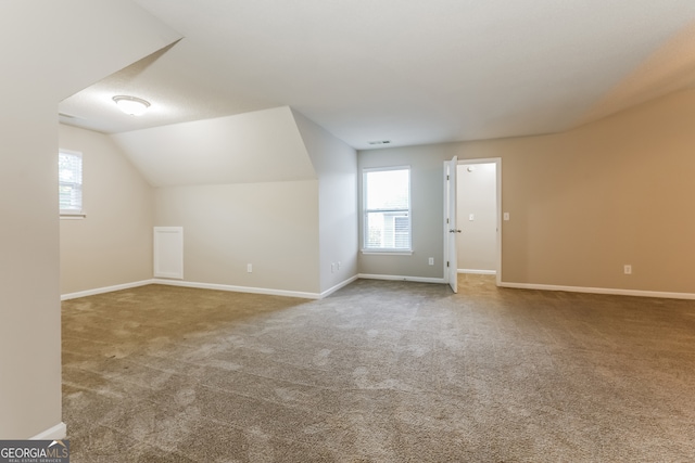 additional living space featuring carpet floors and vaulted ceiling