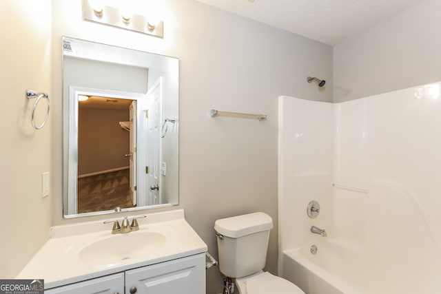 full bathroom featuring vanity, a textured ceiling, toilet, and  shower combination