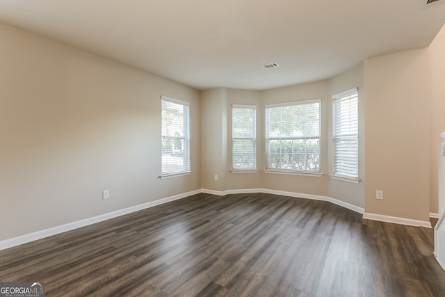 empty room featuring dark hardwood / wood-style flooring and a wealth of natural light