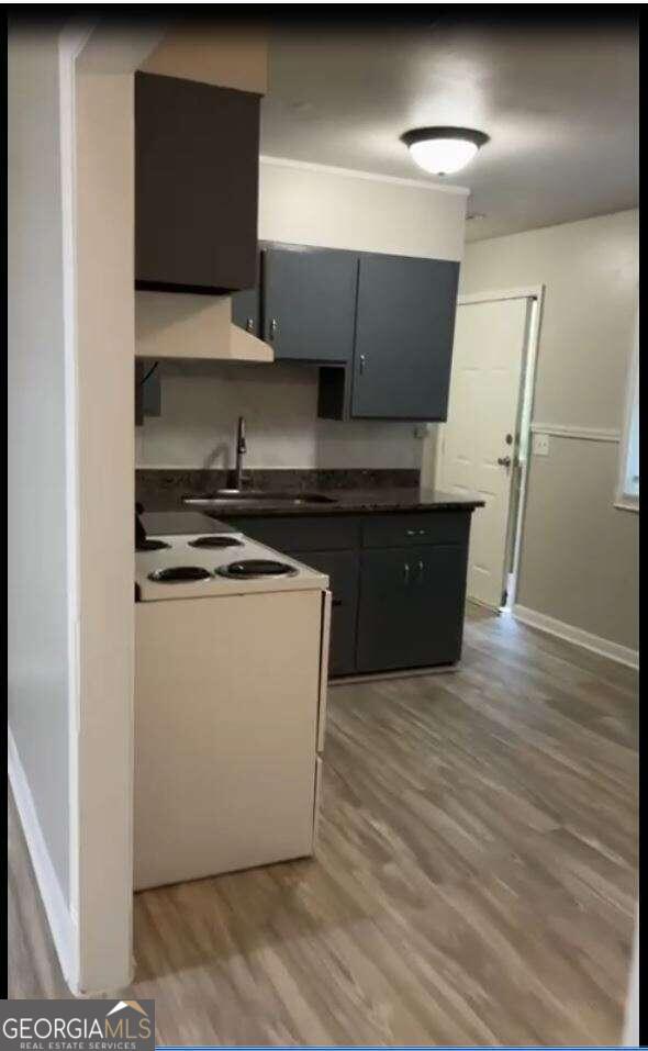 kitchen featuring white range with electric cooktop, sink, and hardwood / wood-style floors