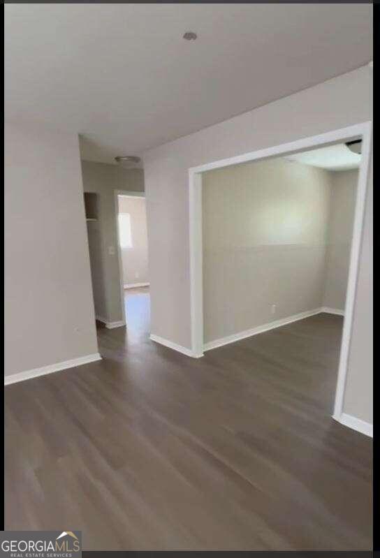 unfurnished room with dark wood-type flooring