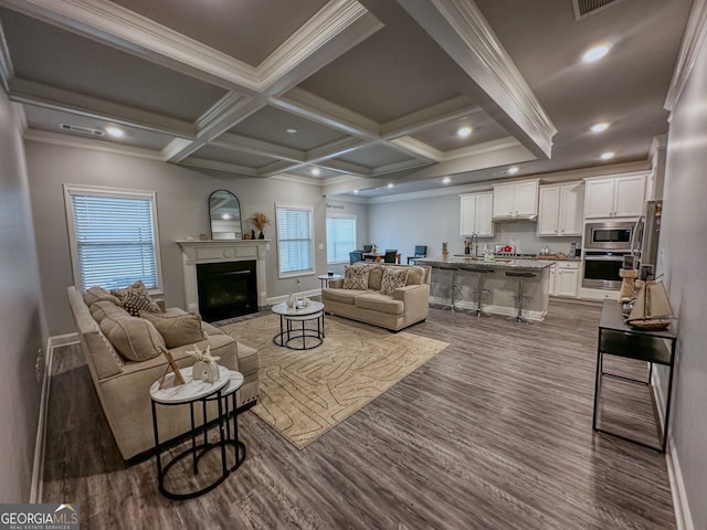 living room with beam ceiling, coffered ceiling, dark hardwood / wood-style floors, and ornamental molding