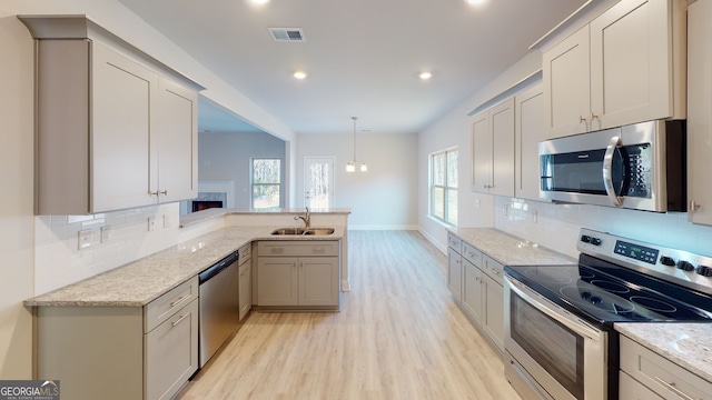 kitchen with appliances with stainless steel finishes, light hardwood / wood-style floors, gray cabinetry, and sink