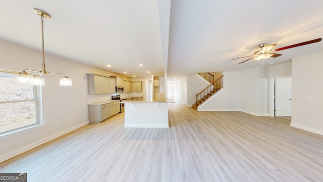 unfurnished living room featuring a high end fireplace, ceiling fan with notable chandelier, and light hardwood / wood-style flooring