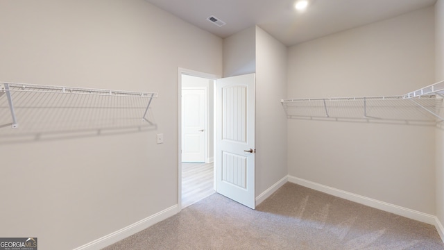 spacious closet featuring light colored carpet