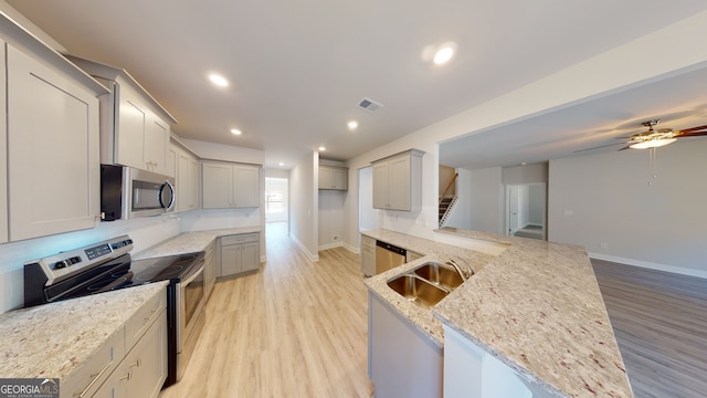 kitchen with kitchen peninsula, tasteful backsplash, stainless steel appliances, light hardwood / wood-style floors, and hanging light fixtures