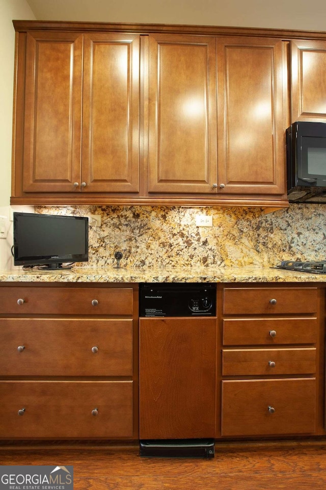 kitchen with decorative backsplash, light stone counters, dark wood-type flooring, and black appliances