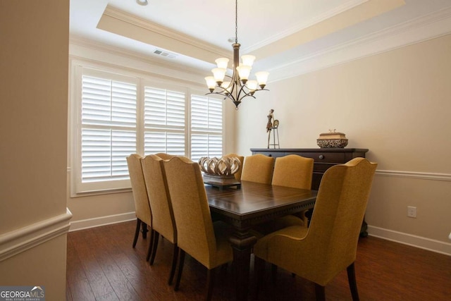 dining space with a tray ceiling, an inviting chandelier, dark hardwood / wood-style floors, and crown molding