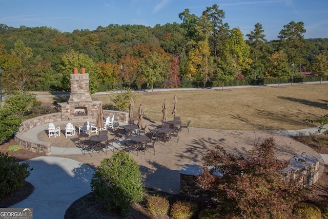 view of yard featuring an outdoor stone fireplace and a patio area