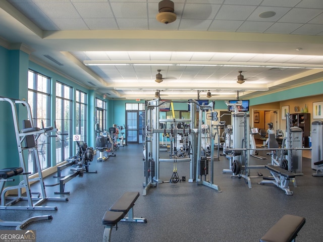 exercise room featuring a drop ceiling, crown molding, and a wealth of natural light