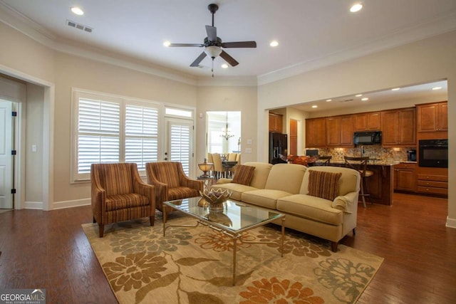 living room featuring ceiling fan with notable chandelier, ornamental molding, and dark wood-type flooring