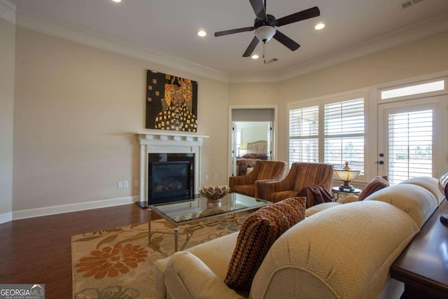 living room with dark wood-type flooring, ceiling fan, and crown molding