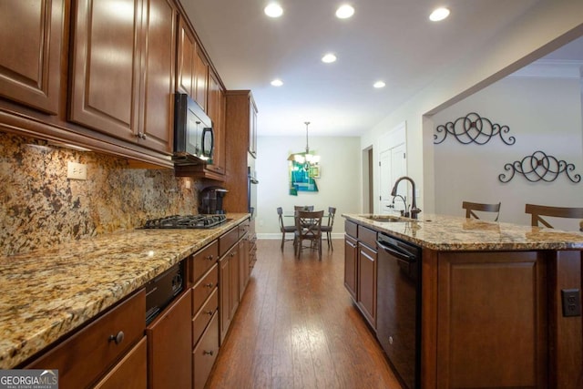 kitchen featuring sink, a breakfast bar area, an island with sink, dark hardwood / wood-style flooring, and stainless steel appliances