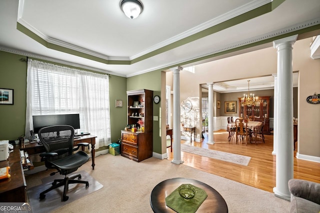 office space with ornate columns, an inviting chandelier, wood-type flooring, a tray ceiling, and ornamental molding