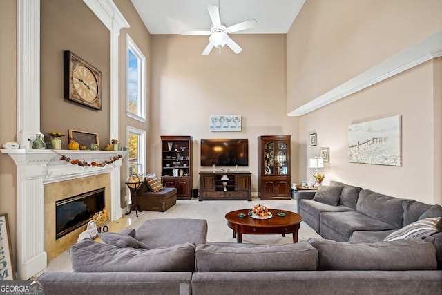 living room with a high end fireplace, a towering ceiling, and ceiling fan