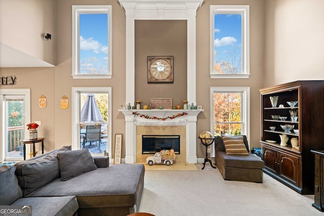 carpeted living room featuring a towering ceiling, a wealth of natural light, and crown molding