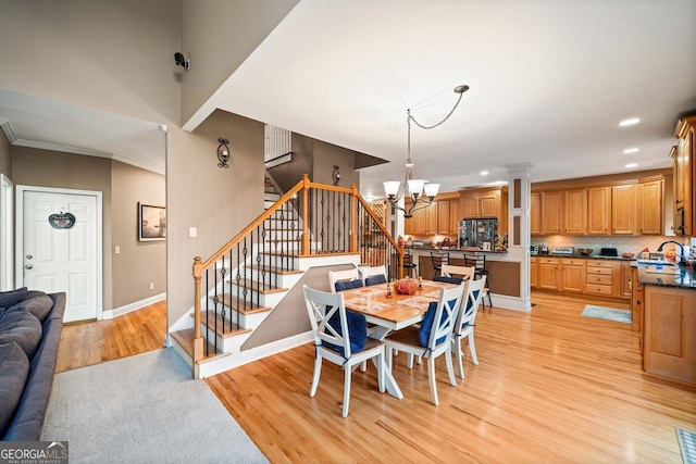 dining area featuring ornamental molding, light hardwood / wood-style flooring, and a notable chandelier