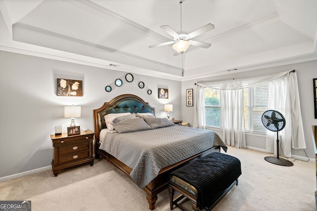 carpeted bedroom with a tray ceiling, ceiling fan, and ornamental molding