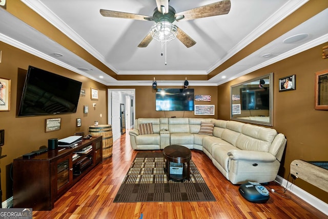 living room featuring hardwood / wood-style flooring, a raised ceiling, ceiling fan, and ornamental molding