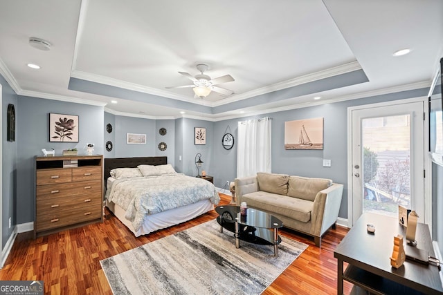 bedroom with ceiling fan, a raised ceiling, wood-type flooring, access to outside, and ornamental molding