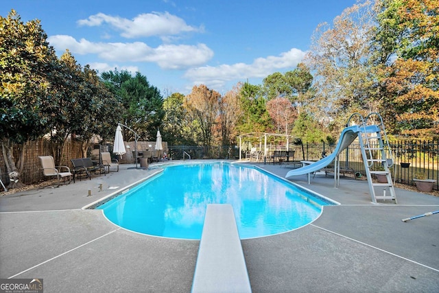 view of pool with a diving board, a patio area, and a water slide